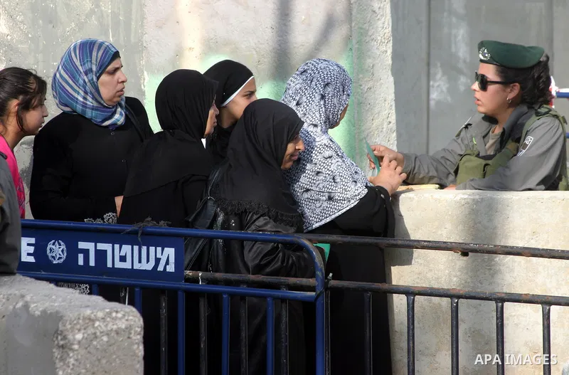 Israeli border policemen check the IDs of the Palestinian female worshippers as they waiting in line to pass at Qalandia checkpoint that leads from the West Bank town of Ramallah to Jerusalem on Aug. 5, 2011, in order to...