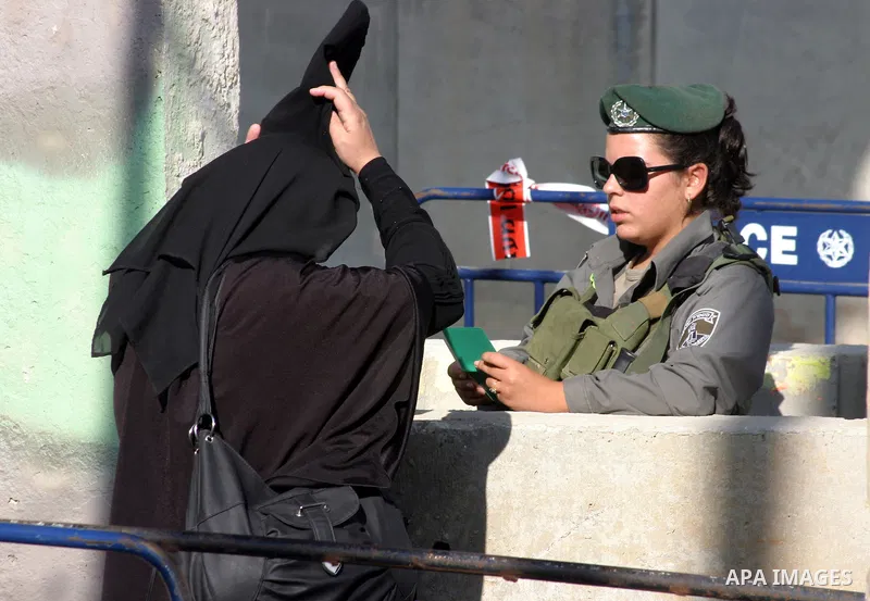 Israeli border policemen check the IDs of the Palestinian female worshippers as they waiting in line to pass at Qalandia checkpoint that leads from the West Bank town of Ramallah to Jerusalem on Aug. 5, 2011, in order to...