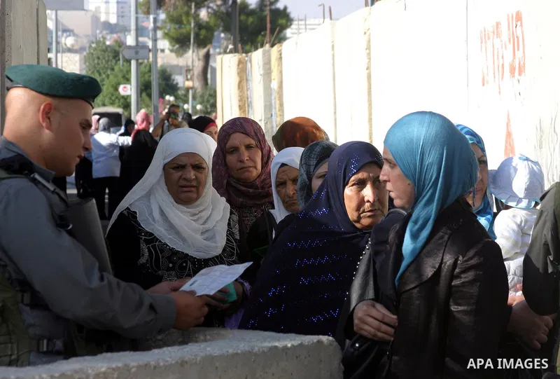 Israeli border policemen check the IDs of the Palestinian female worshippers as they waiting in line to pass at Qalandia checkpoint that leads from the West Bank town of Ramallah to Jerusalem on Aug. 5, 2011, in order to...
