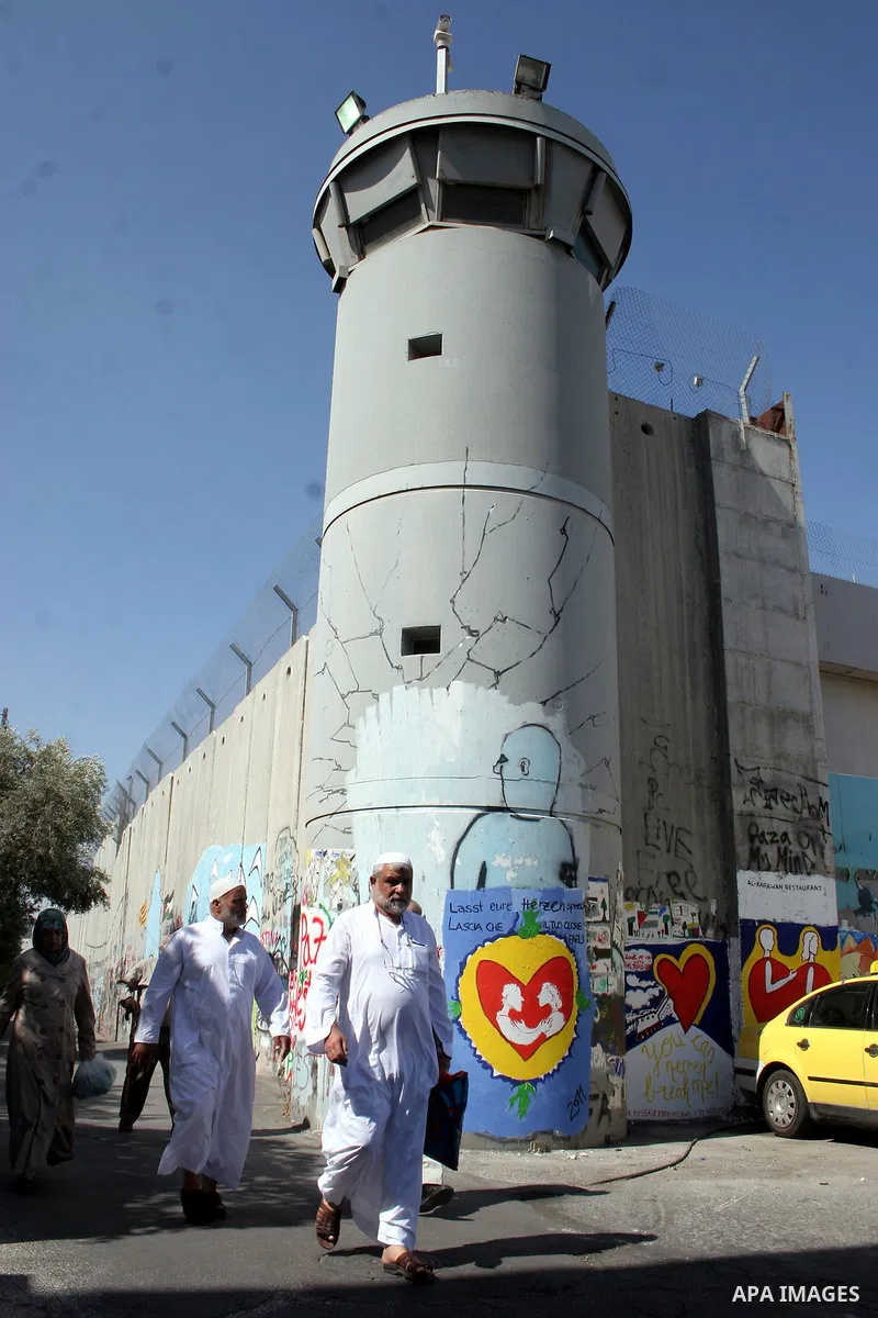 A Palestinian man walks past a mural painted on a section of the controversial Israeli barrier near an Israeli checkpoint to Jerusalem in the West Bank city of Bethlehem during the first Friday of the holy month of Ramad...