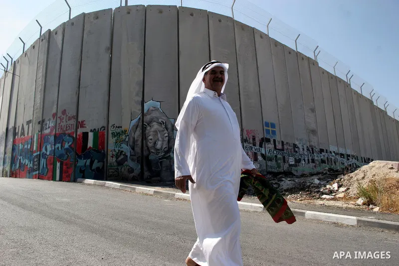 A Palestinian man walks past a mural painted on a section of the controversial Israeli barrier near an Israeli checkpoint to Jerusalem in the West Bank city of Bethlehem during the first Friday of the holy month of Ramad...