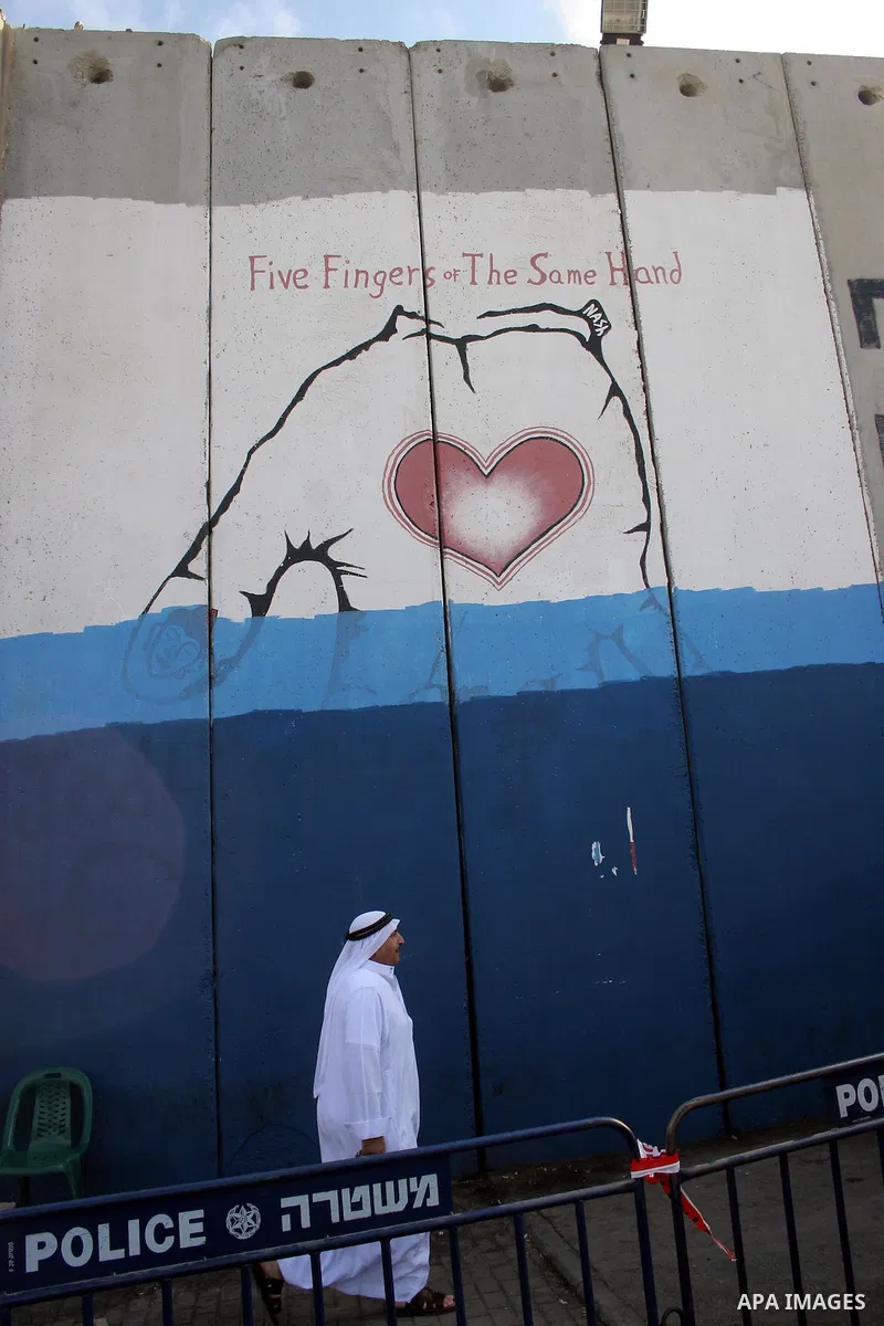 A Palestinian man walks past a mural painted on a section of the controversial Israeli barrier near an Israeli checkpoint to Jerusalem in the West Bank city of Bethlehem during the first Friday of the holy month of Ramad...