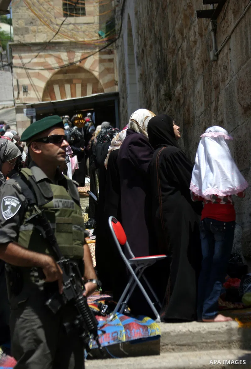 Israeli soldiers stand guard as Palestinian women perform the first Friday prayer of the holy Muslim month of Ramadan in front of the closed Ibrahimi mosque in the West Bank city of Hebron on Aug. 5, 2011. Photo by Najeh...