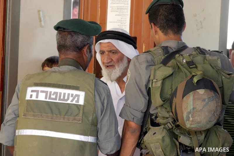 Israeli soldiers stand guard as Palestinian men perform the first Friday prayer of the holy Muslim month of Ramadan in front of the closed Ibrahimi mosque in the West Bank city of Hebron on Aug. 5, 2011. Photo by Najeh H...
