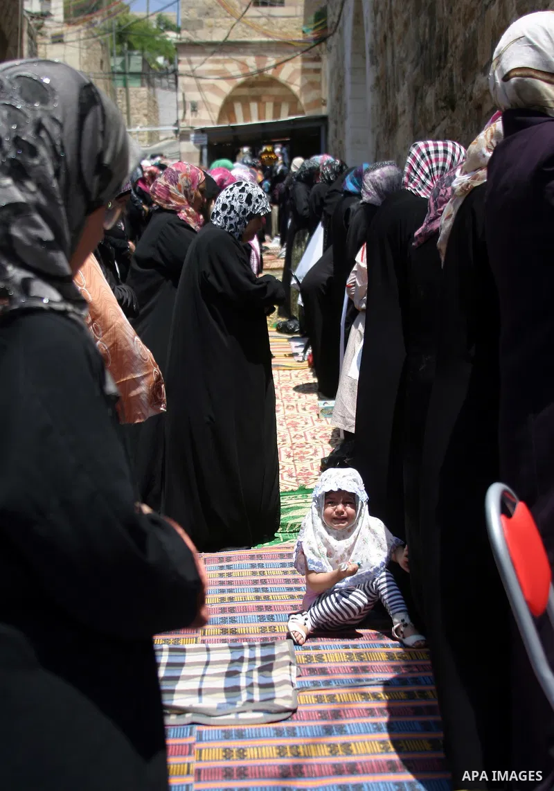 Israeli soldiers (not seen) stand guard as the Palestinian women perform the first Friday prayer of the holy Muslim month of Ramadan in front of the closed Ibrahimi mosque in the West Bank city of Hebron, August 05 2011....