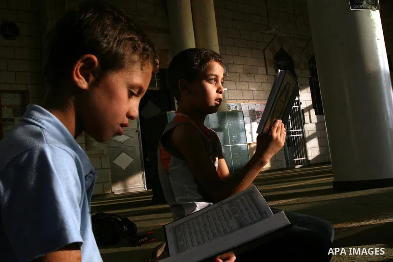 Palestinian boys read the holy Koran at the Big Mosque in the West Bank town of Ramallah, during the Muslim holy fasting month of Ramadan, on Aug. 6, 2011. Muslims throughout the world are celebrating the holy fasting mo...