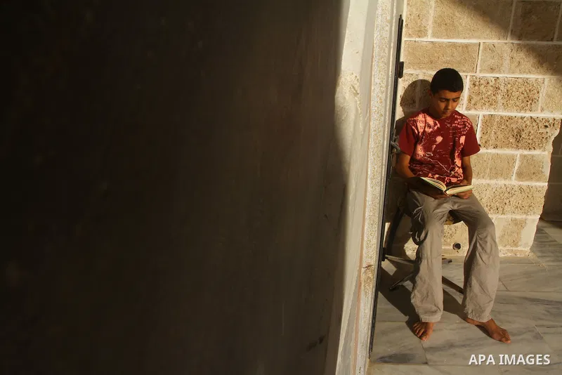 A Palestinian boy reads the holy Koran at al-Omari Mosque in Gaza city, during the Muslim holy fasting month of Ramadan, on Aug. 6, 2011. Muslims throughout the world are celebrating the holy fasting month of Ramadan, th...