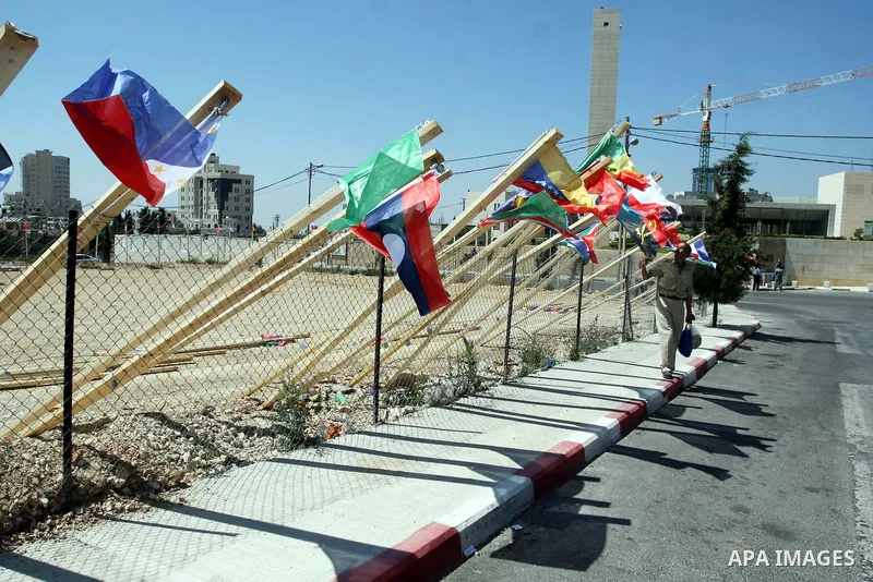 A Palestinian man stands past flags of countries that have recognised the Palestinian state in the West Bank city of Ramallah on Aug. 7, 2011. The flags were raised by local youth groups ahead of the U.N. General Assembl...
