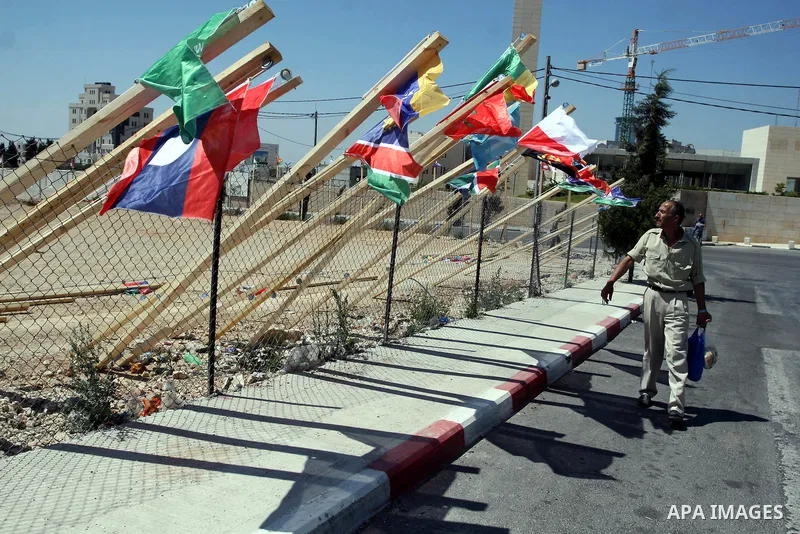 A Palestinian man walks past flags of countries that have recognised the Palestinian state in the West Bank city of Ramallah on Aug. 7, 2011. The flags were raised by local youth groups ahead of the U.N. General Assembly...