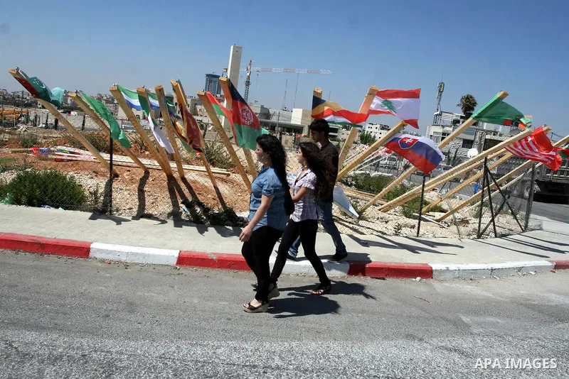 Palestinian women walk past flags of countries that have recognised the Palestinian state in the West Bank city of Ramallah on Aug. 7, 2011. The flags were raised by local youth groups ahead of the U.N. General Assembly...