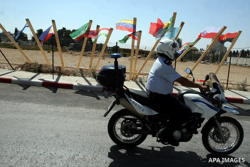 A Palestinian policeman drives his motorcycle near flags of countries that have recognised the Palestinian state in the West Bank city of Ramallah on Aug. 7, 2011. The flags were raised by local youth groups ahead of the...