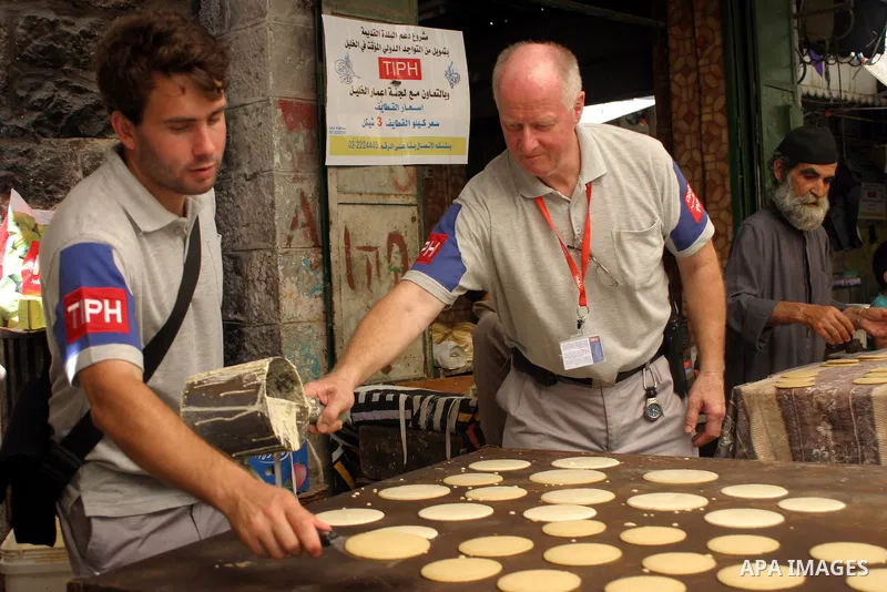 An international observer assists Palestinian shop owners in the old city of Hebron while preparing Ramadan sweets, in the divided West Bank city of Hebron on Aug. 9 2011. According to media report, temporary Internation...