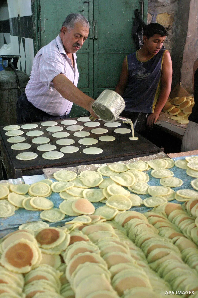 Palestinian vendors prepare qatayef, a pancake-like shell which is filled with nuts or sweet cheese, fried in oil or baked then dipped in sugar syrup, a popular sweet during Ramadan, in a shop in the West Bank city of He...