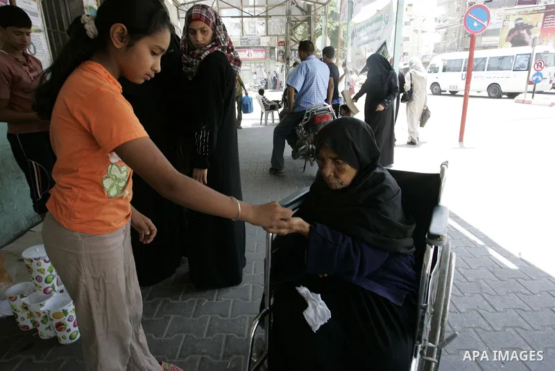 A Palestinian girl gives the charity "Zakat" to a poor woman sitting on her wheelchair at a market in the holiest month of Ramadan in Rafah, southern Gaza Strip on Aug. 11, 2011. Muslims throughout the world are marking...