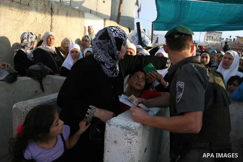Palestinian women wait in line to pass through the Kalandia checkpoint from the West Bank town of Ramallah to Jerusalem, 12 August 2011, to attend the second Friday prayers in the Muslim holy month of Ramadan at al-Aqsa...