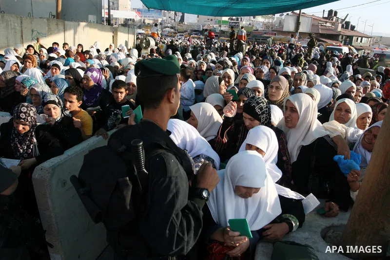 Palestinian women wait in line to pass through the Kalandia checkpoint from the West Bank town of Ramallah to Jerusalem, 12 August 2011, to attend the second Friday prayers in the Muslim holy month of Ramadan at al-Aqsa...