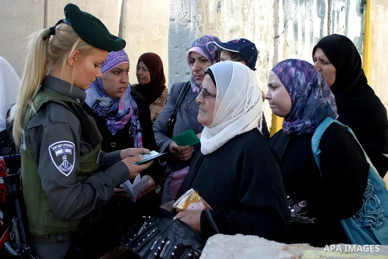 Palestinian Muslims walk through an Israeli checkpoint on the outskirts of the West Bank city of Bethlehem on August 12, 2011 as they wait to cross into Jerusalem to attend the second Friday prayers of the holy fasting m...