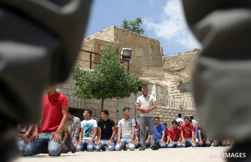 An Israeli soldier stands guard as Palestinians perform the second friday prayer of Islam's holy fasting month of Ramadan outside the Ibrahimi mosque, or the Tomb of the Patriarchs, in the divided West Bank city of Hebro...