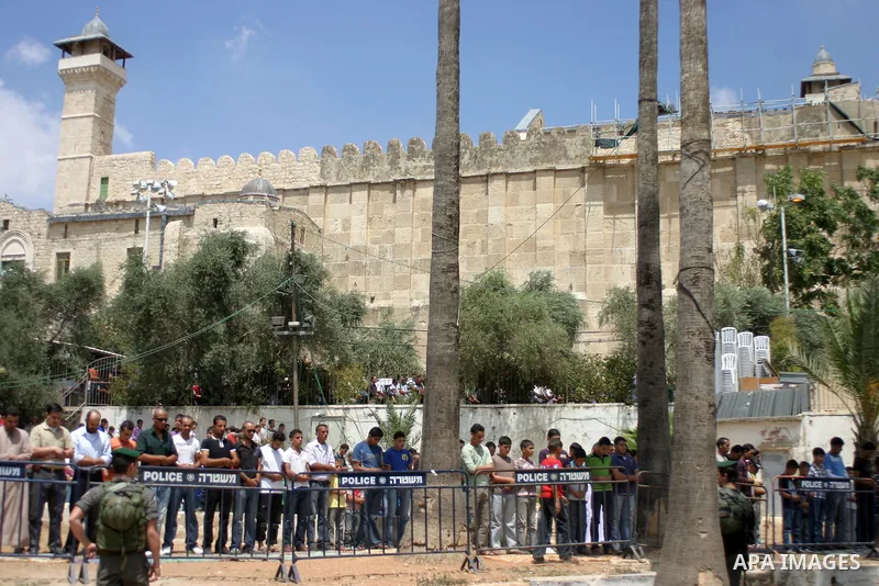 An Israeli soldier stands guard as Palestinians perform the second friday prayer of Islam's holy fasting month of Ramadan outside the Ibrahimi mosque, or the Tomb of the Patriarchs, in the divided West Bank city of Hebro...