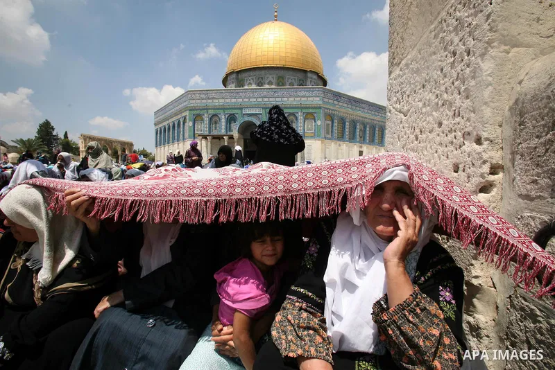 Palestinian worshippers use a prayer mat for shade on the compound known to Muslims as al-Haram al-Sharif and to Jews as Temple Mount before prayers on the third Friday of the holy month of Ramadan in Jerusalem's Old Cit...
