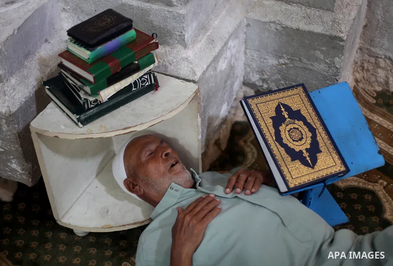Palestinian man rest as others pray and read the Koran in a mosque during the holy month of Ramadan in Central of Gaza City on 12 August 2011. Muslims around the world are observing the holy fasting month of Ramadan in w...