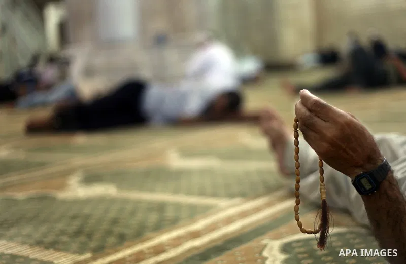 Palestinian man rest as others pray and read the Koran in a mosque during the holy month of Ramadan in Central of Gaza City on 12 August 2011. Muslims around the world are observing the holy fasting month of Ramadan in w...