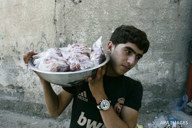 A Palestinian boy participates in the distribution of meat on the homes of the poor and needy on the thirteenth day at the occasion of the holy fasting month of Ramadan in Rafah, southern Gaza Strip on Aug. 13, 2011. whe...