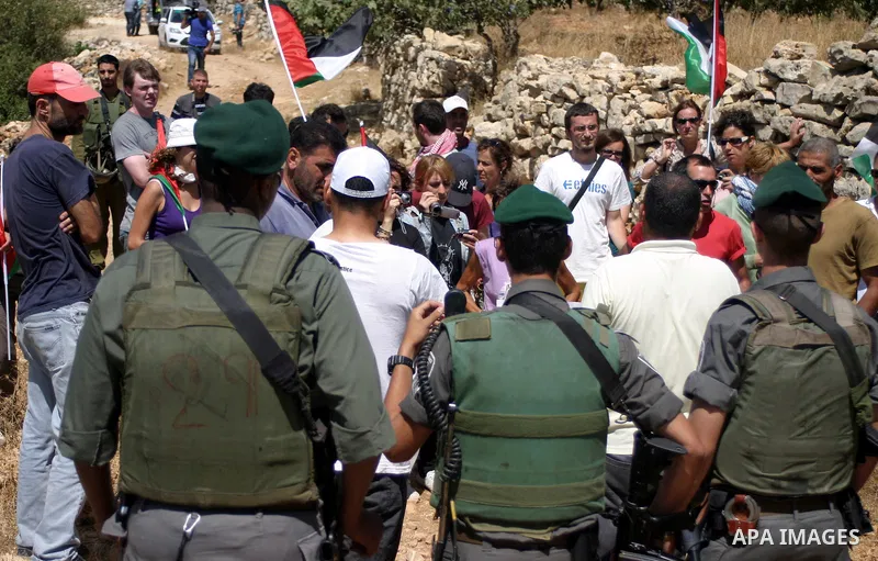 Israeli soldiers scuffle with Palestinian, Israeli and foreign activists during a demonstration against the cof farm land to be used in the construction of Jewish settlements near the existing Israeli settlement of Karmi...