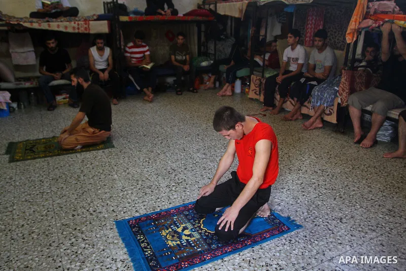A Palestinian prisoner rest as others pray and read the Koran in a Hamas-run jail on the fourteenth day during the holy month of Ramadan Gaza City on Aug. 14, 2011. Muslims around the world are observing the holy fasting...