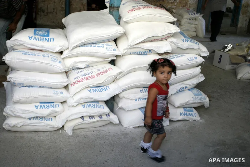 A Palestinian girl walks near food aids receiving from the United Nations Relief and Works Agency (UNRWA) at the Rafah refugee camp, in the southern Gaza Strip on August 15, 2011. USAID halted humanitarian assistance to...