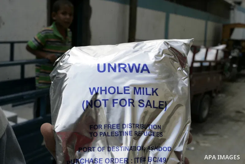 A Palestinian youth carries a bag of milk as others receive food aids from the United Nations Relief and Works Agency (UNRWA) at the Rafah refugee camp, in the southern Gaza Strip on August 15, 2011. USAID halted humanit...