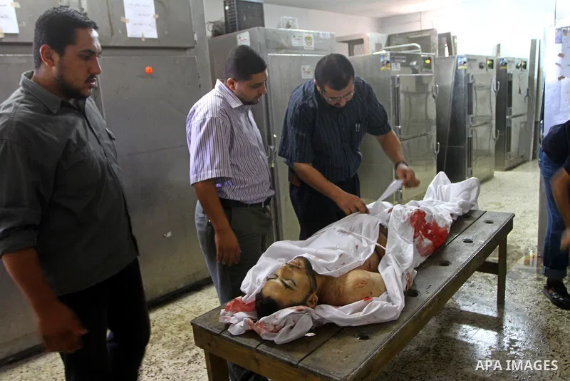 Palestinian relatives stand next to the body of Hamas militant Moussa Shtewi, 29, at the morgue in a hospital in Gaza City, Tuesday, on Aug. 16, 2011. Israeli aircraft struck five targets in the Hamas-ruled Gaza Strip on...