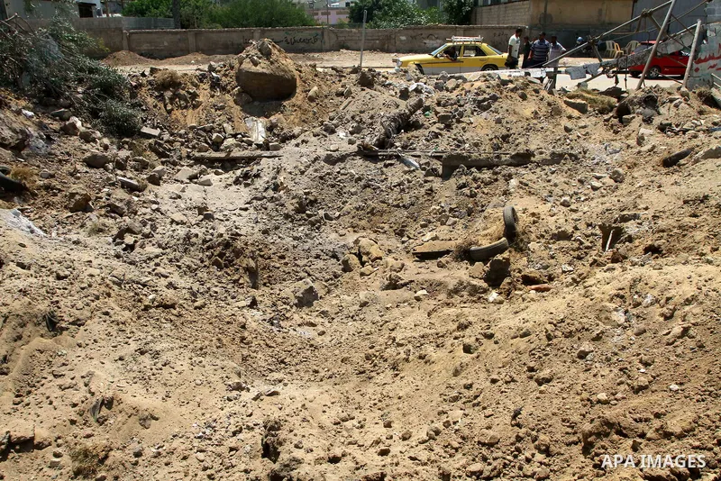 Palestinians stand at the site of an Israeli air strike in Gaza City on August 16, 2011 after one Palestinian was killed and seven injured by overnight Israeli air strikes across the Gaza Strip, Palestinian medics said....