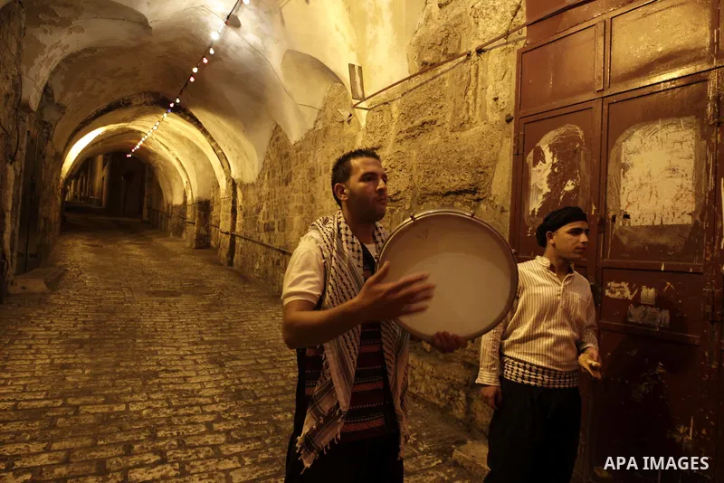 Palestinian youths use a traditional drum to wake up people for their Suhoor in a narrow street leading to the al-Aqsa Mosque in Jerusalem's Old City on August 16,2011, during the sixteenth day of the Muslim holy month o...