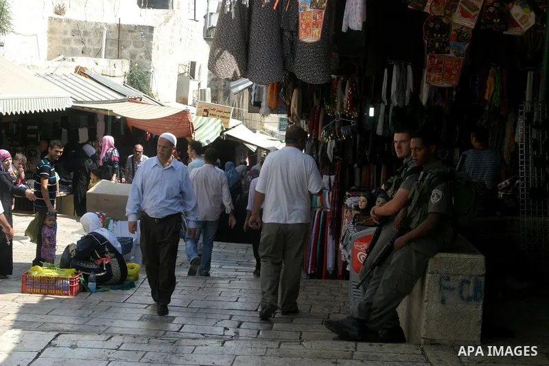 Palestinians walk past Israeli soldiers in the main market Jerusalem's Old City on August 16,2011, during the sixteenth day of the Muslim holy month of Ramadan. Photo by Mahfouz Abu Turk