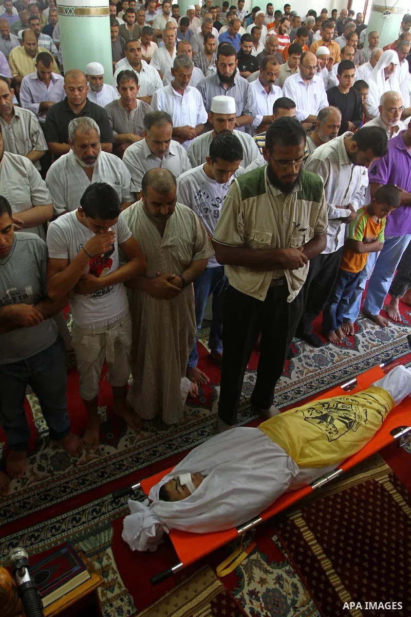 Palestinian mourners pray on the body of Saad al-Majdalali before his funeral in the central Gaza Strip refugee camp of Nusseirat on August 17, 2011 a day after Israeli troops shot and killed him as he came near to the b...