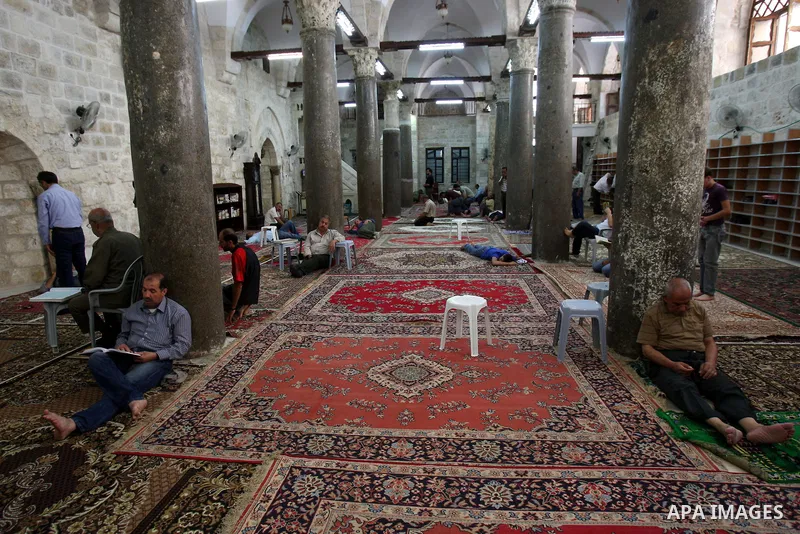 Palestinian Muslims rest as others pray and read the holy Koran at a Mosque during the holy month of Ramadan in the West Bank city of Nablus on Aug. 17, 2011. Muslims around the world are observing the holy fasting month...