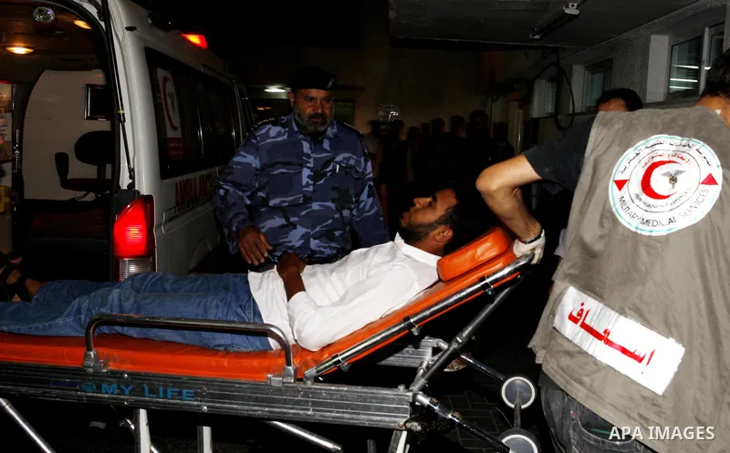 Palestinians wheel a wounded man following an Israeli attack in Gaza City on August 19, 2011. Photo by Mahmud Nassar