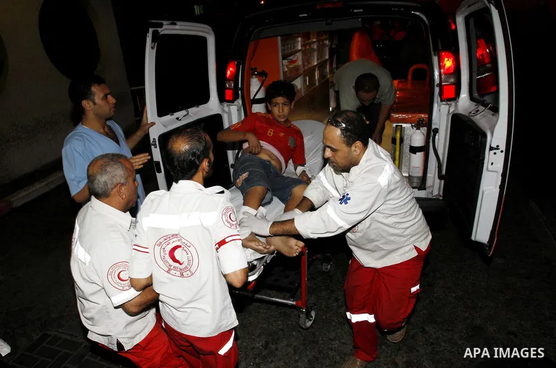 Palestinians wheel a wounded boy following an Israeli attack in Gaza City on August 19, 2011. Photo by Mahmud Nassar