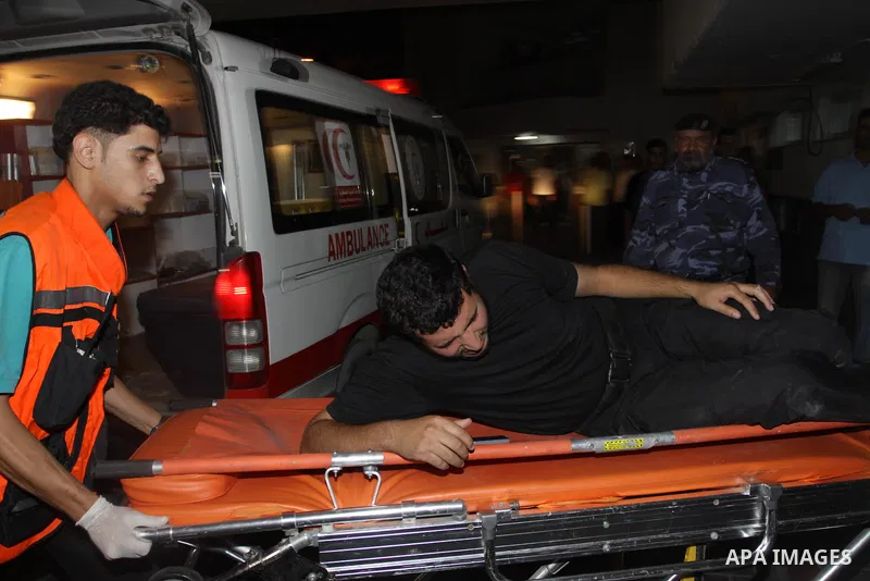 Palestinians wheel a wounded man following an Israeli attack in Gaza City on August 19, 2011. Photo by Mahmud Nassar