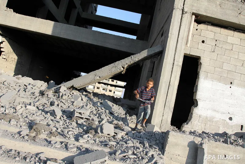 A Palestinian boy stands past a damaged government building after an Israeli air strike in Gaza August 19, 2011. Israeli aircraft struck Hamas security installations in Gaza on Friday, killing at least one Palestinian, i...