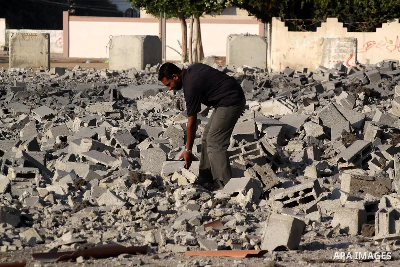 A Palestinian man stands past a damaged government building after an Israeli air strike in Gaza August 19, 2011. Israeli aircraft struck Hamas security installations in Gaza on Friday, killing at least one Palestinian, i...