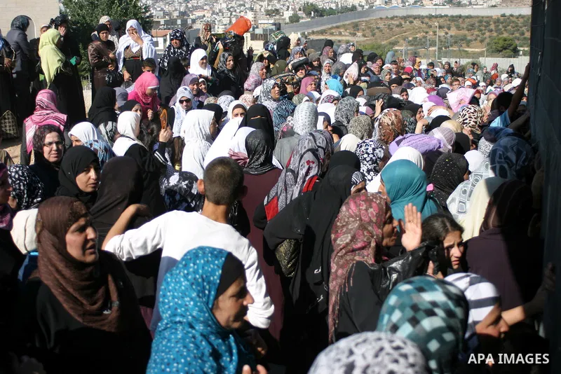 Palestinian Muslims wait at an Israeli checkpoint on the outskirts of the West Bank city of Bethlehem on August 19, 2011 as they wait to cross into Jerusalem to attend on their way to pray at the Al Aqsa Mosque on the th...
