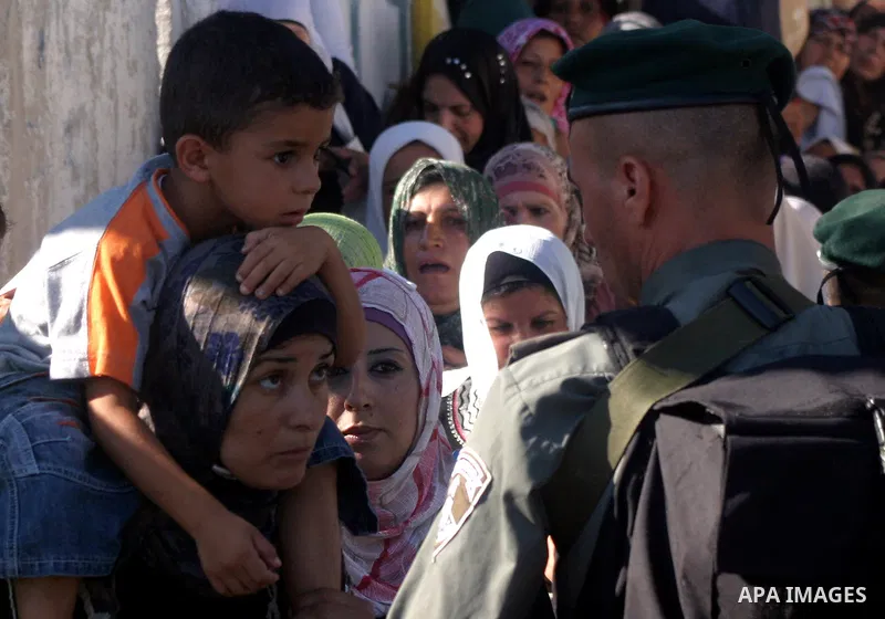 Palestinian Muslims wait at an Israeli checkpoint on the outskirts of the West Bank city of Bethlehem on August 19, 2011 as they wait to cross into Jerusalem to attend on their way to pray at the Al Aqsa Mosque on the th...