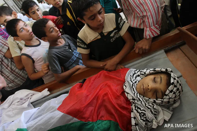Palestinian mourners stand around the body of Mahmoud Abu Samra, 13, killed in an Israeli airstrike early Friday, during his funeral in Gaza City, Aug. 19, 2011. Gaza militants launched barrages of rockets deep into Isra...