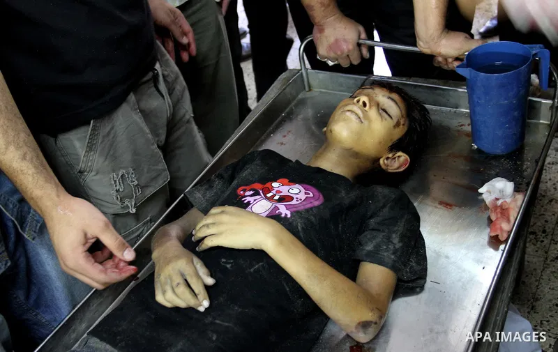 Palestinian mourners stand around the body of Mahmoud Abu Samra, 13, killed in an Israeli airstrike early Friday, during his funeral in Gaza City, Aug. 19, 2011. Gaza militants launched barrages of rockets deep into Isra...
