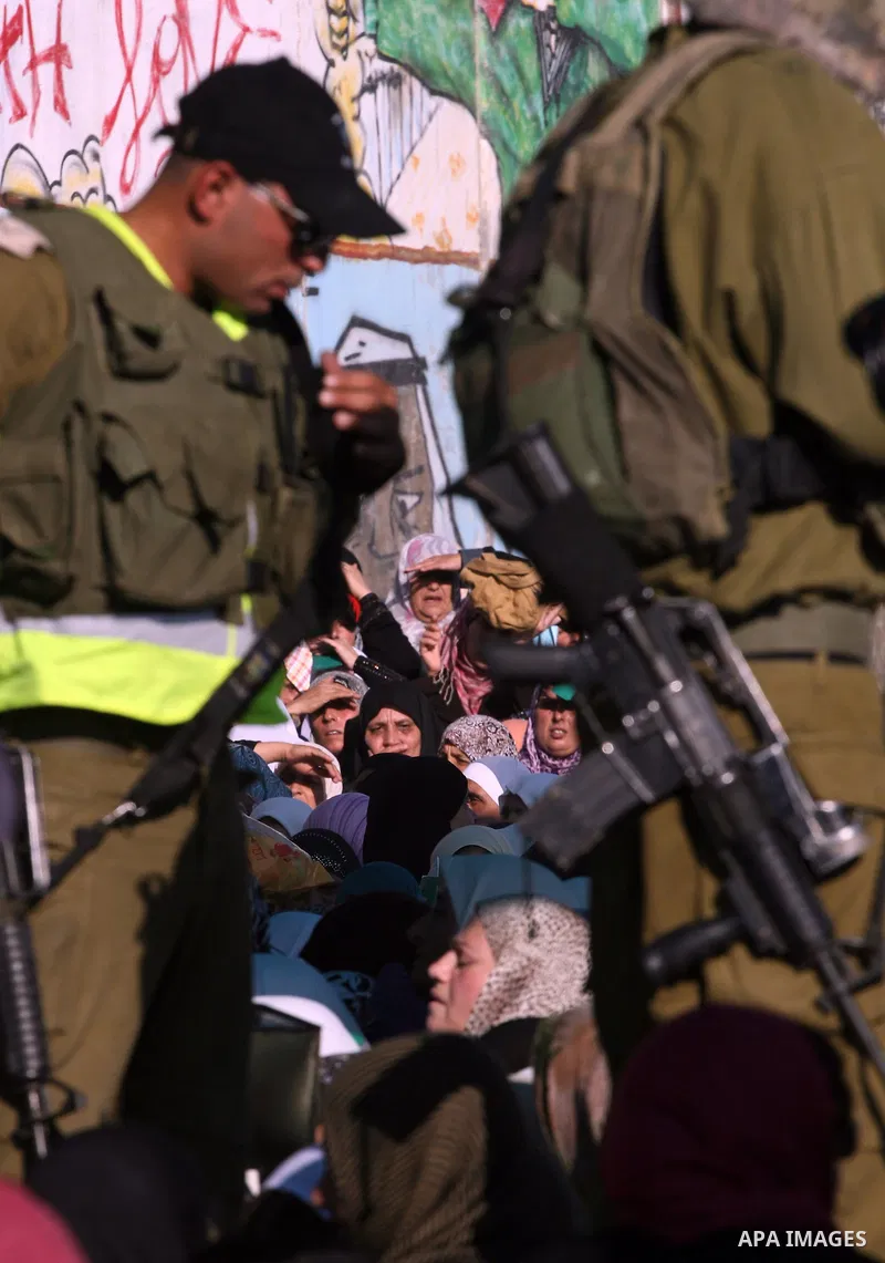 Palestinian women wait to cross the Qalandia checkpoint on their way to pray at the Al Aqsa Mosque on the third Friday of the Muslim holy month of Ramadan, at the Qalandia checkpoint between the West Bank city of Ramalla...