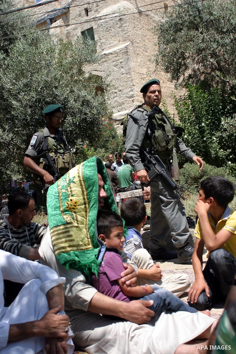 Israeli border guards keep watch as Palestinians attend the third friday prayer of Islam's holy fasting month of Ramadan outside the Ibrahimi mosque, or the Tomb of the Patriarchs, in the divided West Bank city of Hebron...