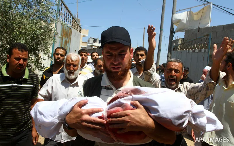 A Palestinian man carries the body of two-year-old boy Malek Sha'at during his funeral in Rafah in the southern Gaza Strip August 19, 2011. An Israeli air strike killed the leader of an armed Palestinian faction, a top l...