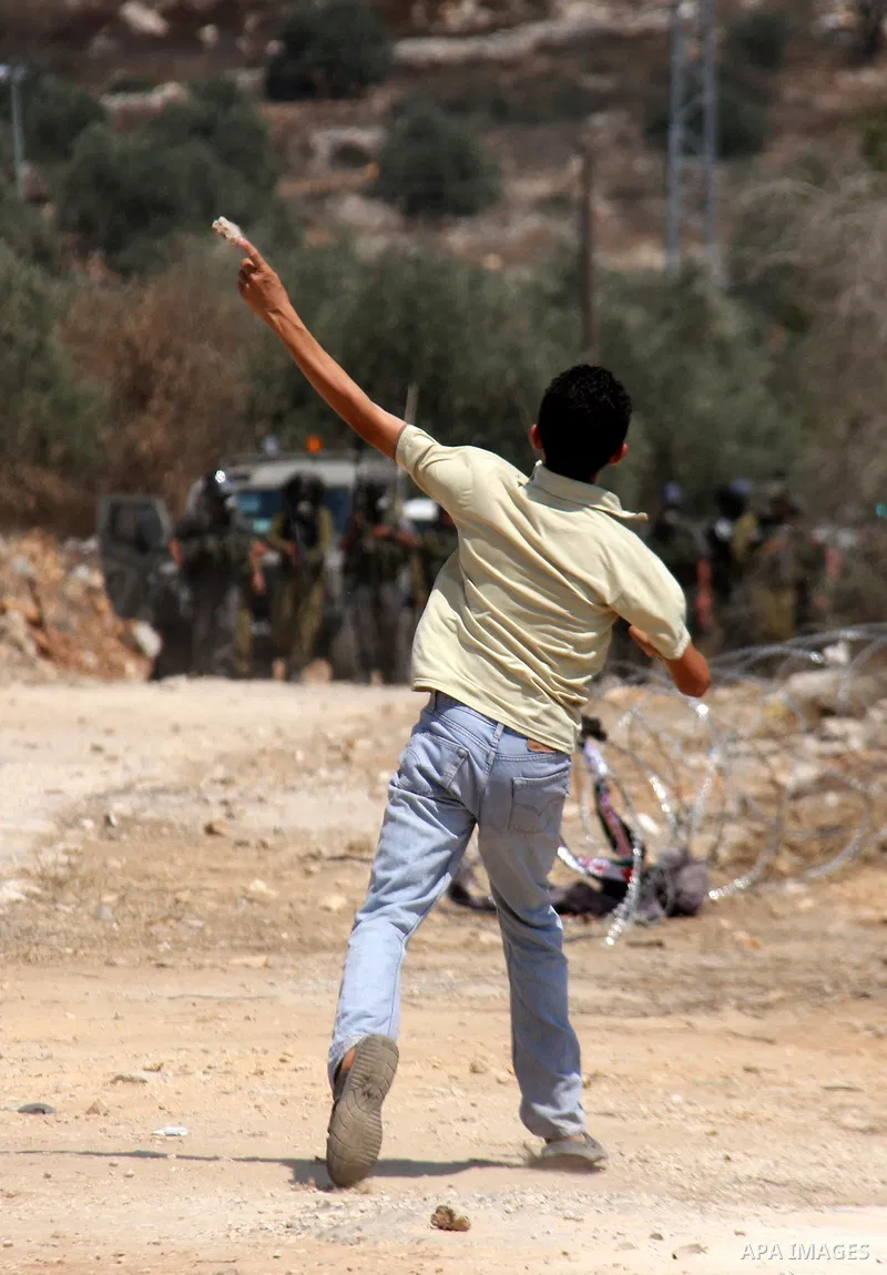 A Palestinian demonstrator throws stones toward Israeli forces during clashes following a protest against the closure of a road during the second Intifada by Jewish settlers from the nearby settlement of Kadumim on Augus...
